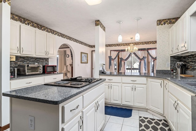 kitchen featuring white cabinets, decorative backsplash, a chandelier, and a center island