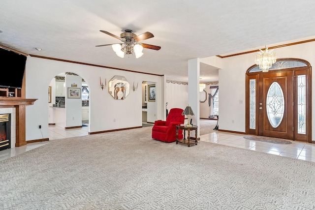 carpeted foyer entrance featuring a textured ceiling, crown molding, ceiling fan with notable chandelier, and a tile fireplace