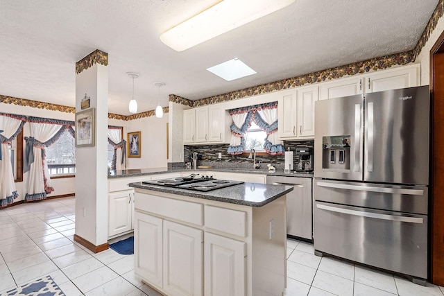 kitchen with white cabinets, appliances with stainless steel finishes, a center island, decorative backsplash, and sink