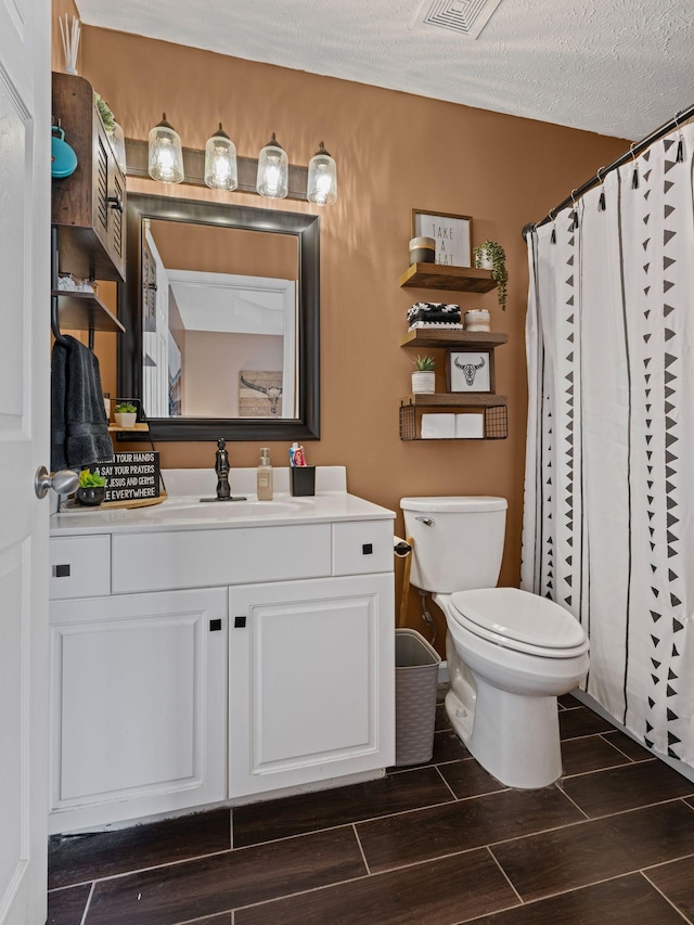 bathroom with vanity, toilet, curtained shower, and a textured ceiling