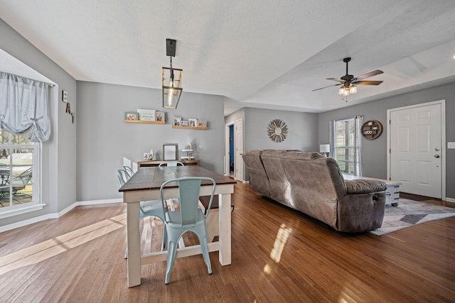 dining space with ceiling fan, wood-type flooring, and a textured ceiling