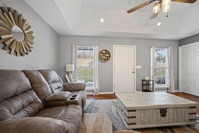 living room with ceiling fan, plenty of natural light, hardwood / wood-style flooring, and a tray ceiling