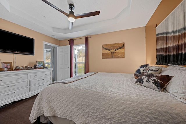 bedroom featuring ceiling fan, dark wood-type flooring, and a raised ceiling