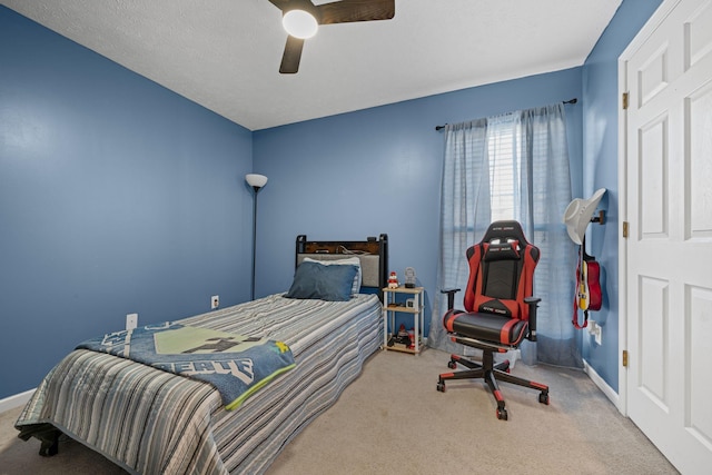 carpeted bedroom with ceiling fan and a textured ceiling