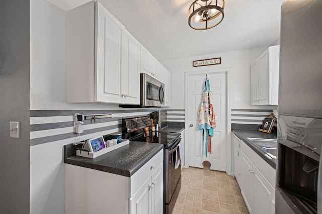 kitchen featuring sink, white cabinetry, appliances with stainless steel finishes, and a textured ceiling