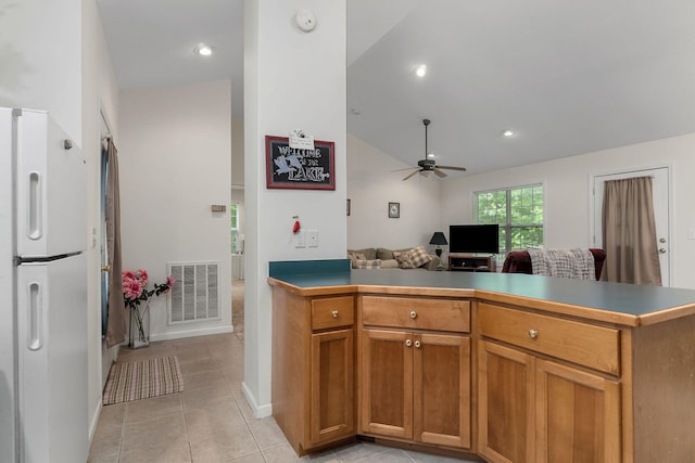 kitchen featuring vaulted ceiling, white refrigerator, kitchen peninsula, light tile patterned flooring, and ceiling fan