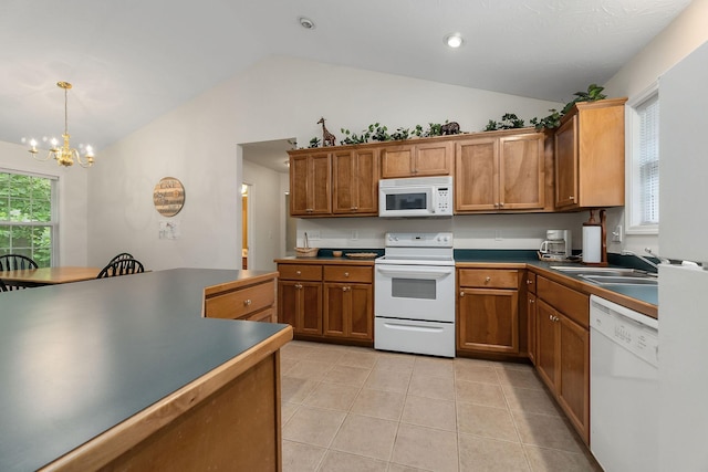 kitchen with an inviting chandelier, decorative light fixtures, white appliances, vaulted ceiling, and sink