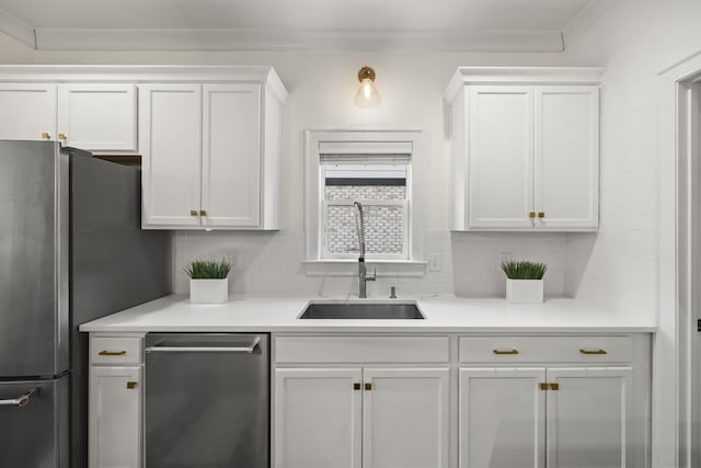 kitchen with white cabinetry, stainless steel appliances, tasteful backsplash, sink, and ornamental molding