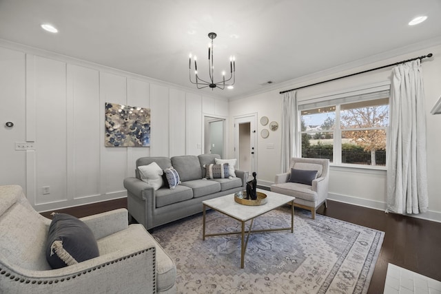 living room with dark wood-type flooring, a notable chandelier, and ornamental molding