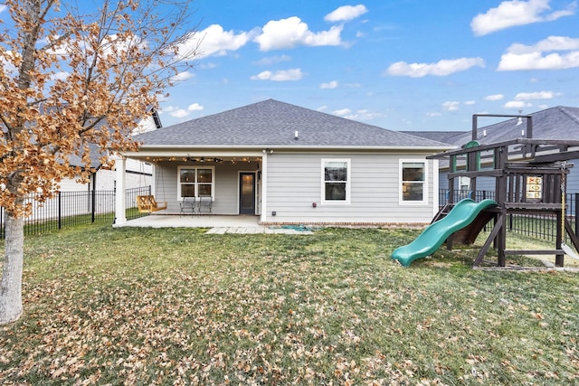 rear view of house with a playground, a yard, and a patio