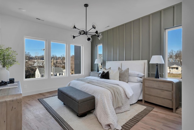 bedroom with multiple windows, a notable chandelier, and light hardwood / wood-style flooring