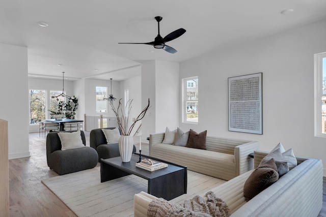 living room with ceiling fan with notable chandelier and light wood-type flooring