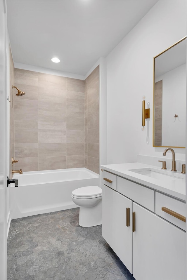 full bathroom with tiled shower / bath, vanity, and toilet