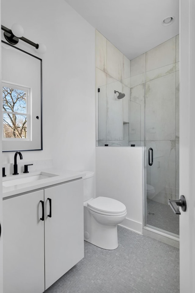 bathroom featuring vanity, toilet, and a shower with shower door