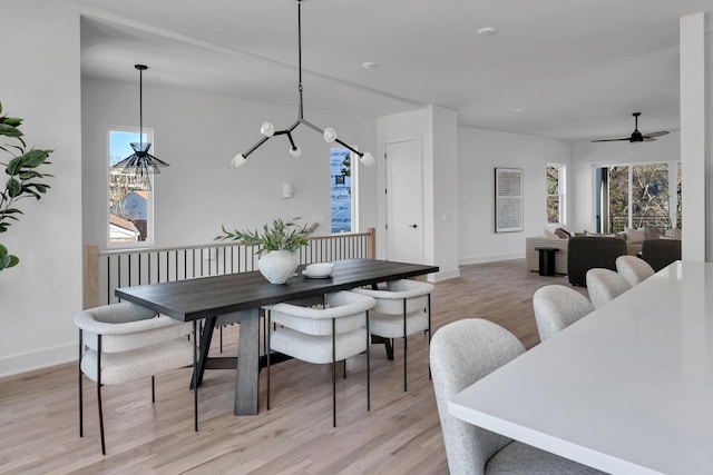 dining area featuring ceiling fan with notable chandelier, a wealth of natural light, and light hardwood / wood-style floors