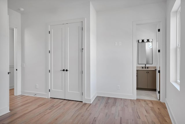 corridor with sink and light wood-type flooring