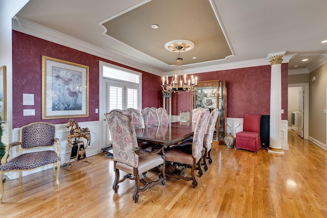 dining area with decorative columns, crown molding, an inviting chandelier, and light hardwood / wood-style floors