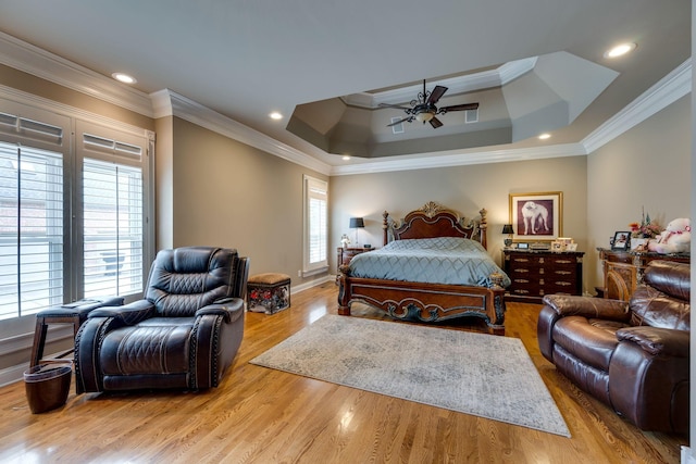 bedroom featuring a raised ceiling, crown molding, ceiling fan, and light hardwood / wood-style flooring