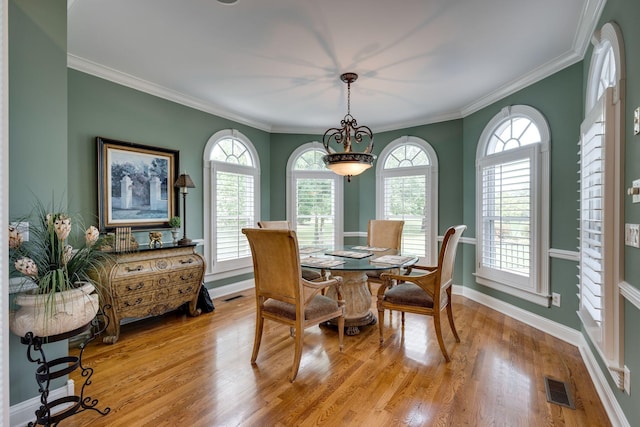 dining area with crown molding and light hardwood / wood-style flooring