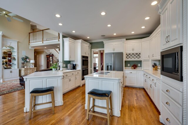 kitchen featuring appliances with stainless steel finishes, white cabinetry, a kitchen breakfast bar, a kitchen island, and kitchen peninsula