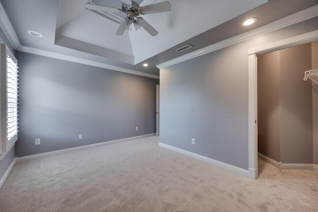 unfurnished room featuring light carpet, ornamental molding, a tray ceiling, a wealth of natural light, and ceiling fan