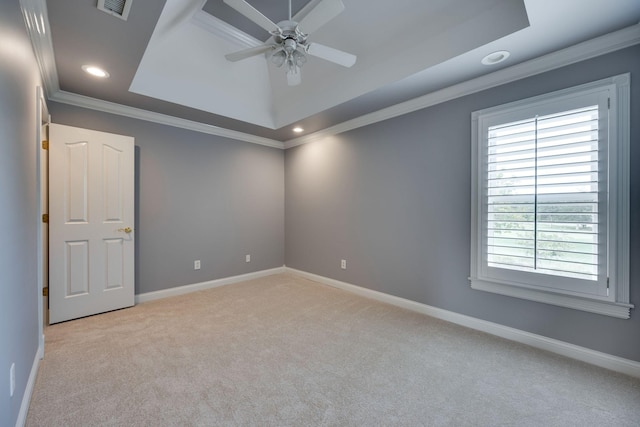 spare room featuring ceiling fan, light colored carpet, ornamental molding, and a raised ceiling