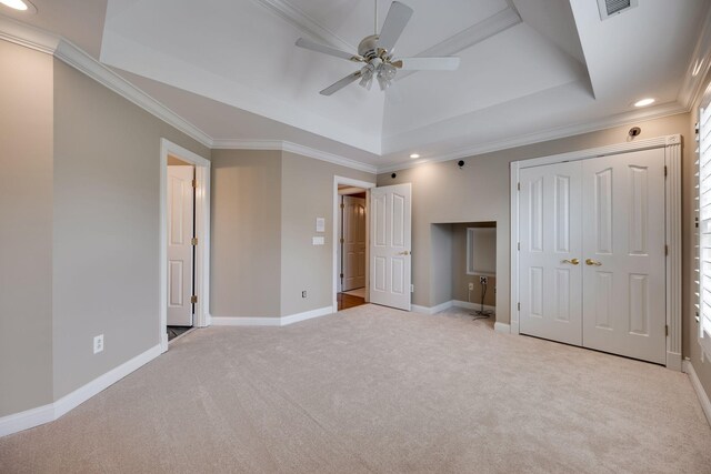 unfurnished bedroom featuring crown molding, ceiling fan, a tray ceiling, light carpet, and a closet