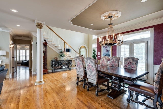 dining space with ornamental molding, decorative columns, light hardwood / wood-style flooring, and a notable chandelier