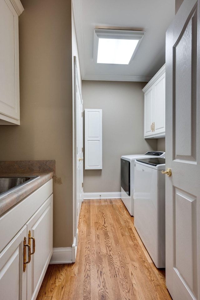 washroom featuring cabinets, washer and clothes dryer, and light hardwood / wood-style floors