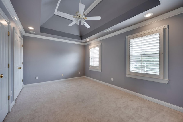 unfurnished room with a raised ceiling, crown molding, light carpet, and ceiling fan