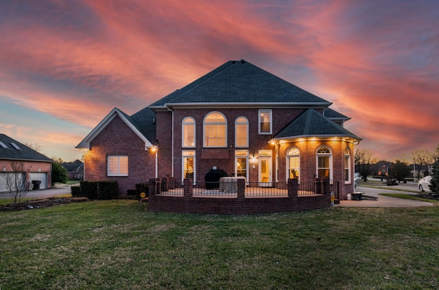 back house at dusk featuring a lawn