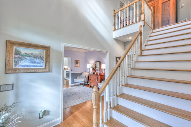 stairway featuring hardwood / wood-style flooring and a towering ceiling