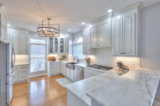 kitchen with decorative light fixtures, backsplash, kitchen peninsula, stainless steel appliances, and a chandelier