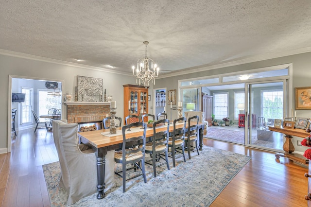 dining area with a multi sided fireplace, a textured ceiling, ornamental molding, and hardwood / wood-style floors