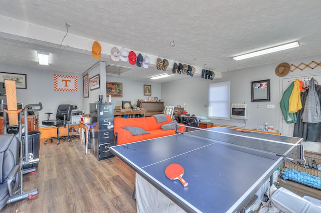 playroom with heating unit, a textured ceiling, and hardwood / wood-style floors