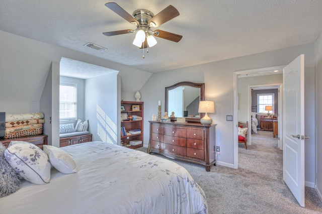 bedroom with ceiling fan, light colored carpet, vaulted ceiling, and multiple windows