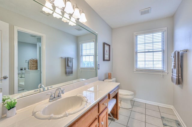 bathroom with toilet, a healthy amount of sunlight, vanity, and tile patterned floors