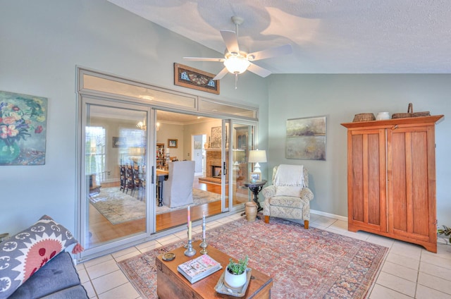 living room with lofted ceiling, ceiling fan, light tile patterned flooring, and a textured ceiling