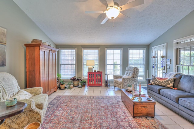 living room with ceiling fan, a textured ceiling, lofted ceiling, and light tile patterned flooring