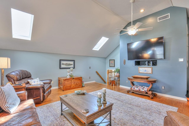 living room with ceiling fan, light hardwood / wood-style flooring, and lofted ceiling with skylight