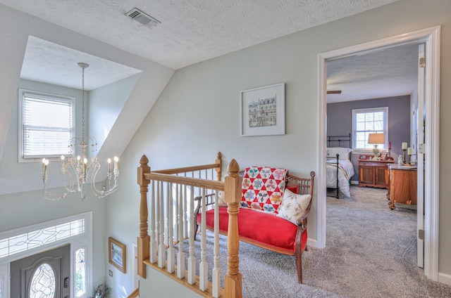 living area with a textured ceiling, lofted ceiling, a notable chandelier, and carpet flooring