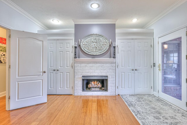 unfurnished living room with a textured ceiling, ornamental molding, a fireplace, and wood-type flooring