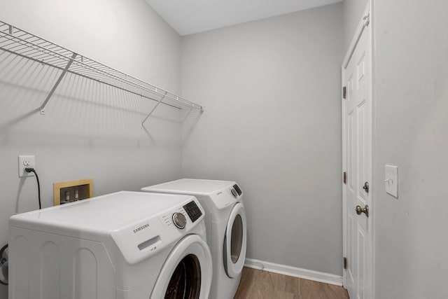 laundry room with washer and clothes dryer and hardwood / wood-style flooring