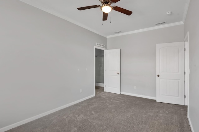 unfurnished bedroom with ceiling fan, ornamental molding, and dark colored carpet