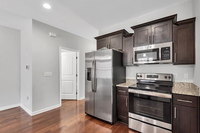 kitchen featuring light stone counters, appliances with stainless steel finishes, dark hardwood / wood-style flooring, and dark brown cabinets