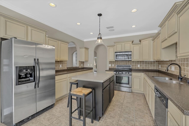 kitchen featuring tasteful backsplash, a kitchen island, a kitchen bar, hanging light fixtures, and appliances with stainless steel finishes