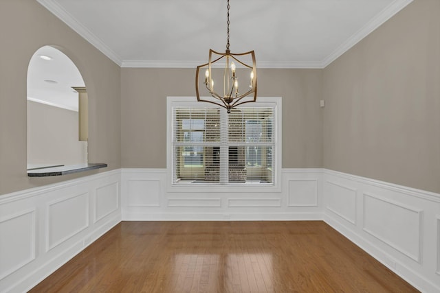 unfurnished dining area with a notable chandelier, crown molding, and hardwood / wood-style floors