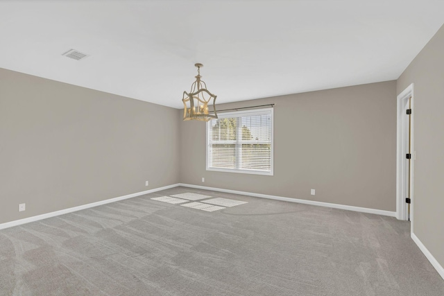 carpeted empty room featuring a chandelier