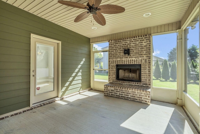 unfurnished sunroom featuring an outdoor brick fireplace, ceiling fan, and a wealth of natural light