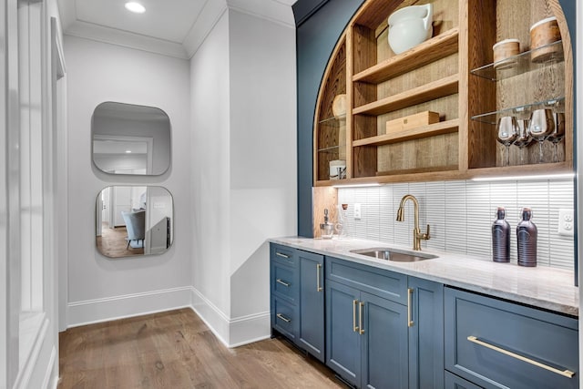 bar with hardwood / wood-style floors, blue cabinetry, tasteful backsplash, ornamental molding, and sink